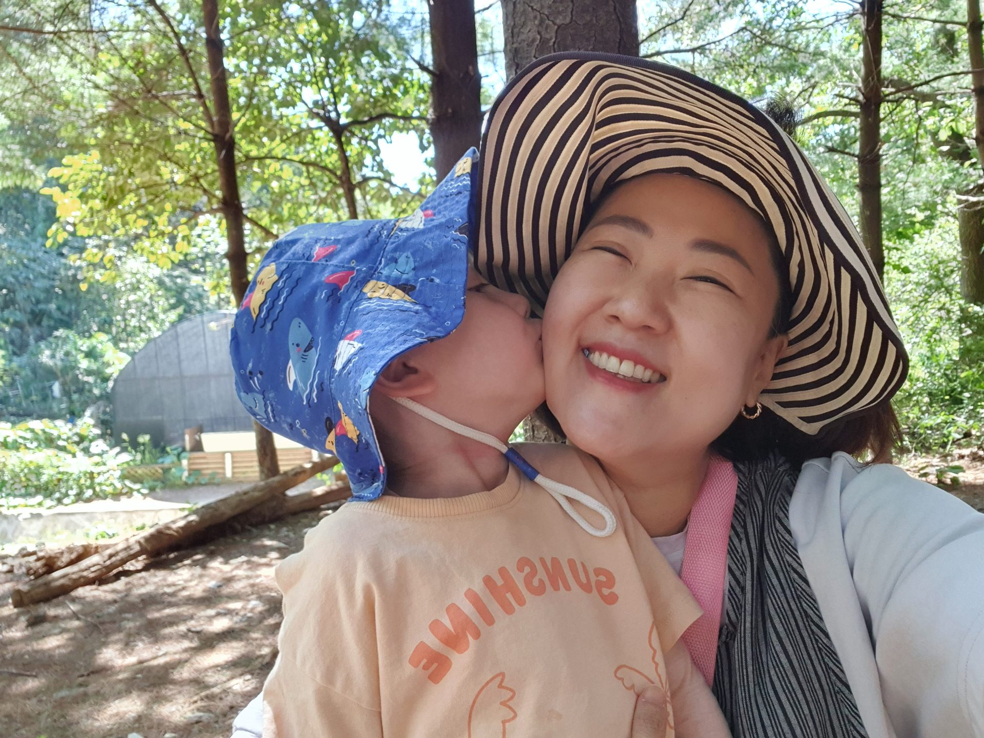 숲체험 중 아이에게 뽀뽀를 받으며 웃고 있는 교사